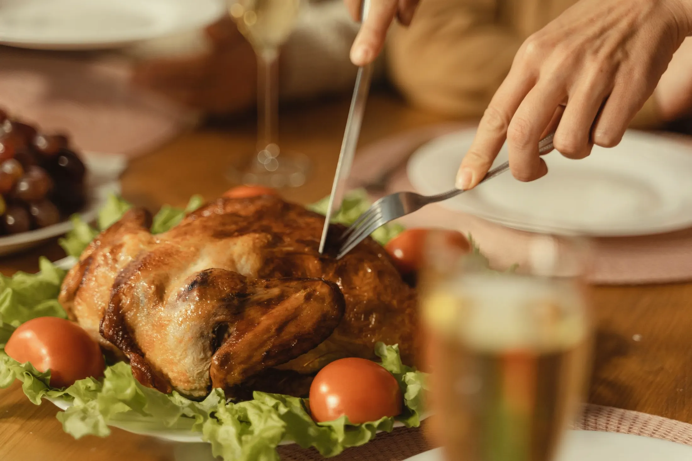 A roast chicken being carved at the table with a fork and knife